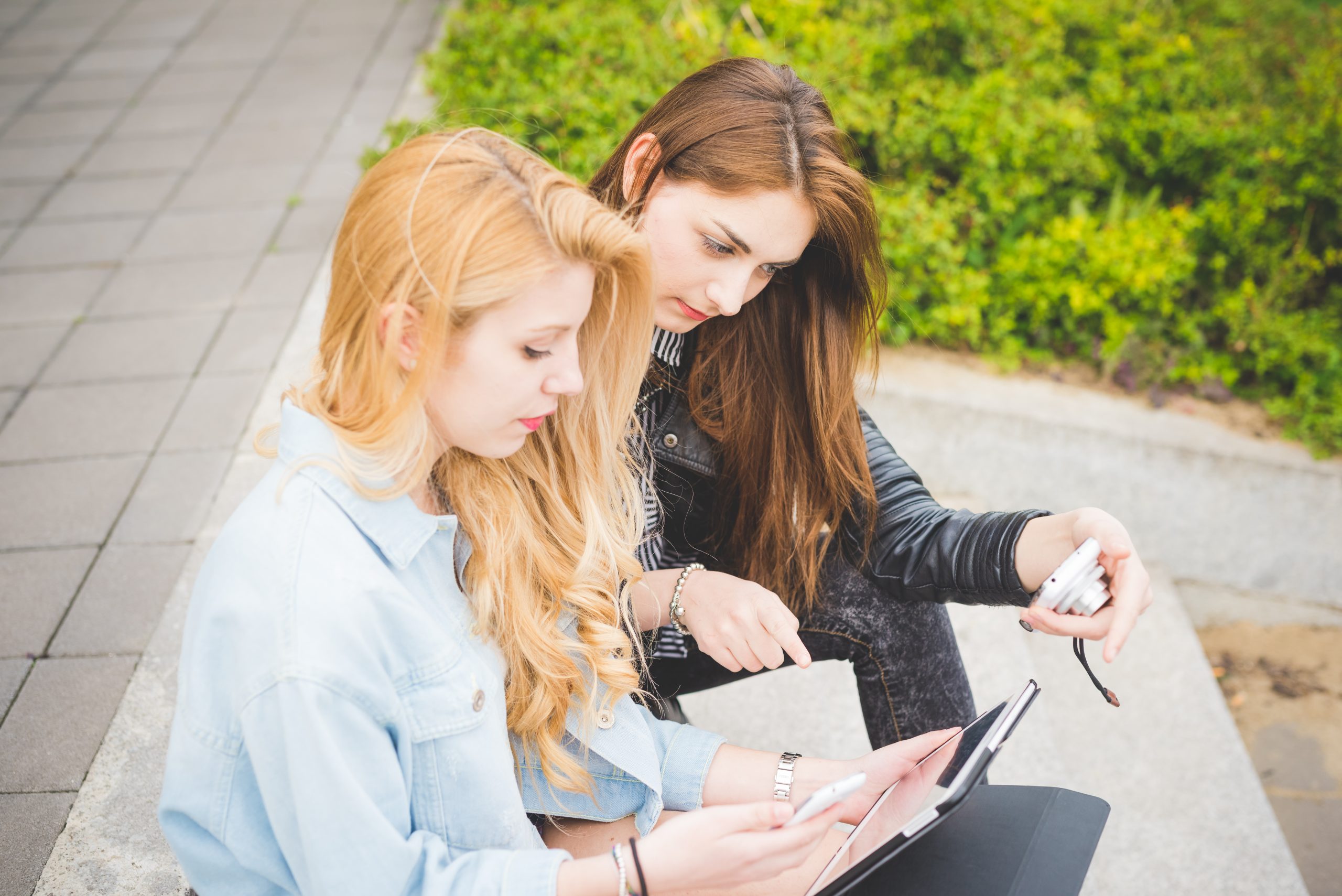 Työssäoppimispaikkanavigaattori – selkeyttä harjoittelupaikkojen hakuun two young girl seated on the ground using a tablet